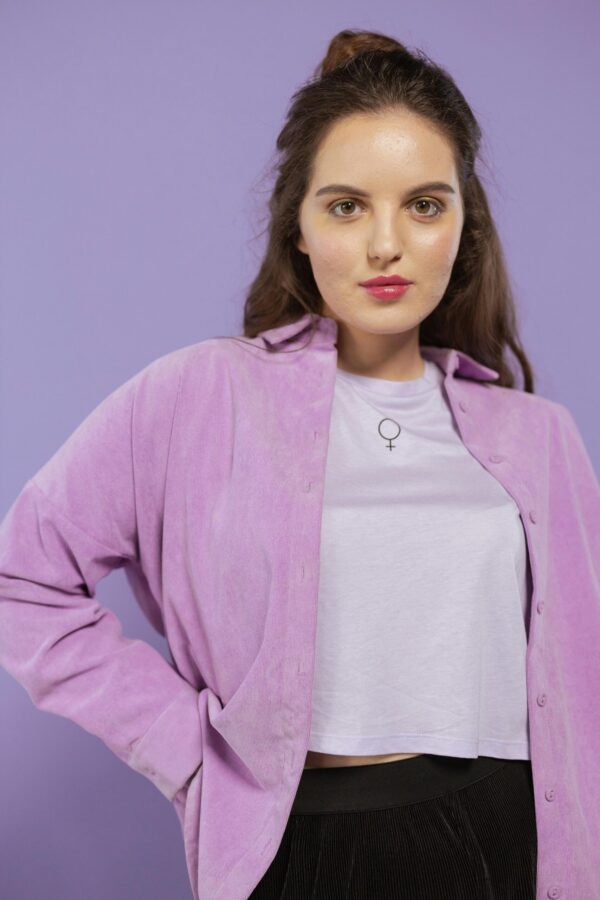 Stylish woman posing in a lavender outfit against a soft background.